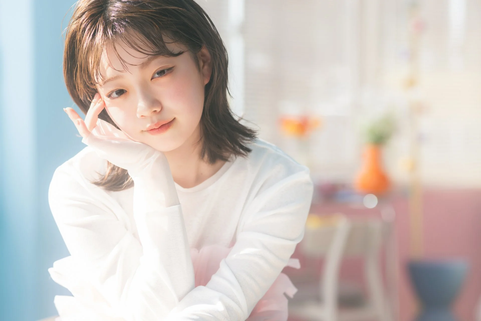 明るい光の中でほほえむミディアムヘアの女性モデル