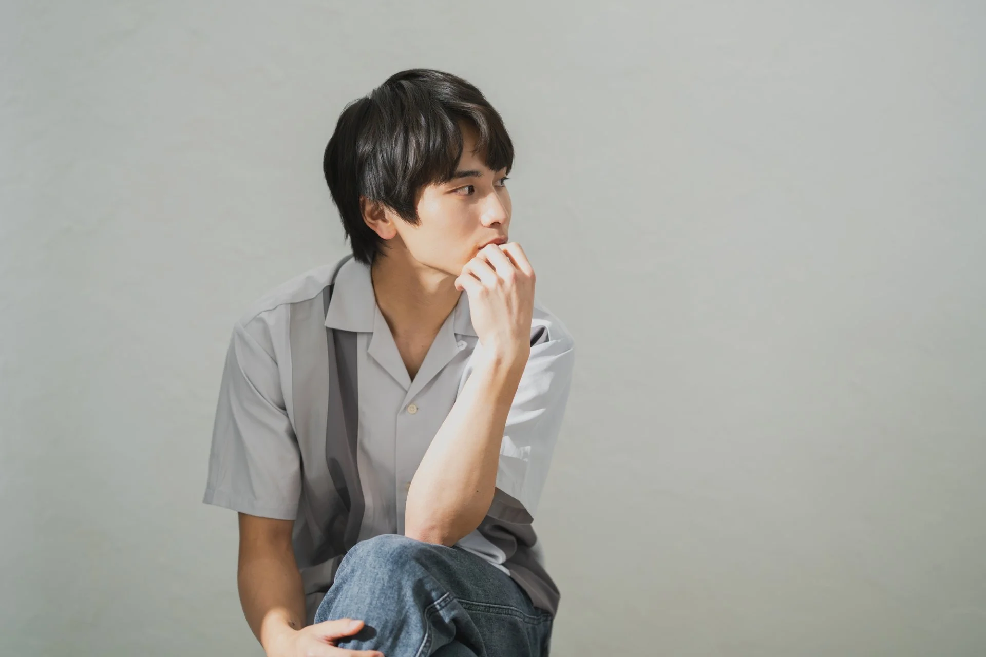 横を向いて物思いにふける黒髪の男性モデル